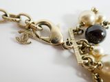 a close up of a necklace with pearls and charms on it