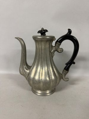 une cafetière ancienne en argent avec une poignée noire sur une surface blanche