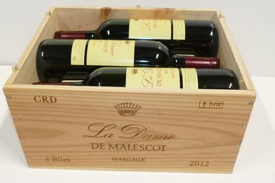 des bouteilles de vin rouge dans un coffret en bois posé sur une surface blanche