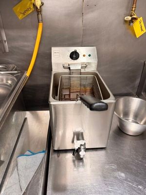 une friteuse dans une cuisine professionnelle, équipée d'un tuyau