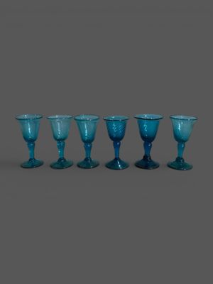 six verres à pied bleus sont alignés en rangée