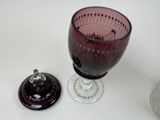 a wine glass sitting next to a glass with a lid on a table