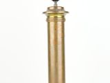 une lampe de table en laiton vieilli surmontée d'un abat-jour noir