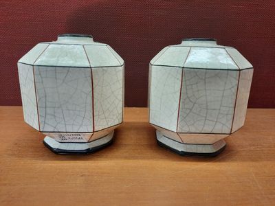 deux vases blancs posés sur une table en bois, avec un mur rouge en arrière-plan