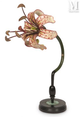 fleur posée sur un socle noir, avec une tige verte et une fleur rose