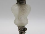 une lampe ancienne en argent et en verre dépoli, posée sur un pied en métal