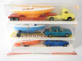 three toy cars and a boat in a display case