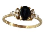 un gros plan d'une bague en or sertie d'une pierre noire et de diamants blancs