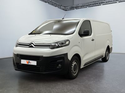 La camionnette blanche est garée dans une grande pièce aux murs blancs.