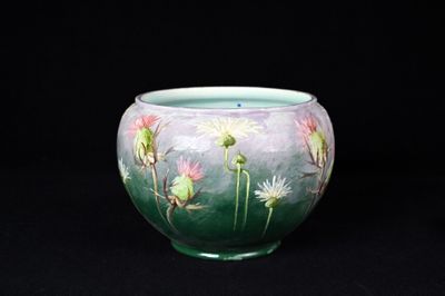 un vase vert orné de fleurs peintes sur fond noir