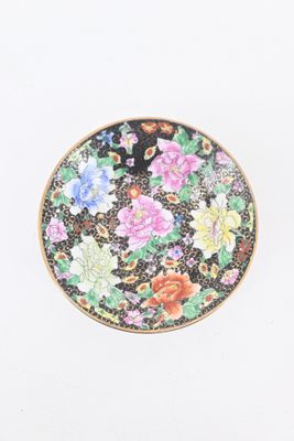 une petite assiette décorée de fleurs, posée sur un fond blanc