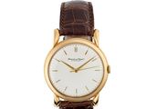 une montre-bracelet en or avec un cadran blanc et un bracelet en cuir marron