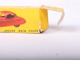 a red toy car in a yellow box on a white surface