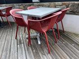 des tables et des chaises sur une terrasse en bois, avec un mur de pierre en arrière-plan