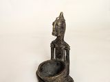 an old bronze statue of a person sitting on a bowl