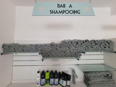 une étagère sur laquelle sont posés des serviettes et des shampoings, dans une salle de bains