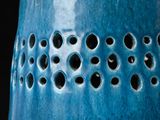 a blue vase with holes in it on a black background