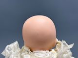 a doll with a white dress and lace on it ' s head