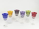 several different colored wine glasses sitting next to each other on a white surface