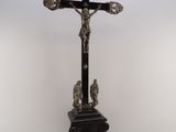 un crucifix ancien posé sur un socle, sur fond blanc
