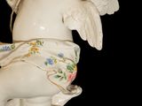 a statue of a cupid holding a tea cup