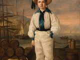 portrait of a boy in a sailor ' s outfit standing on a dock