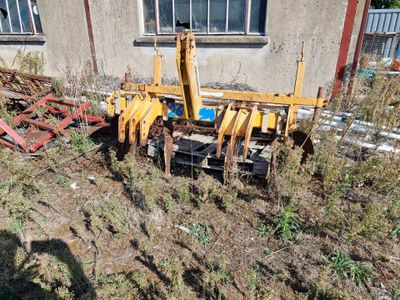 un tracteur qui est garé dans l'herbe près d'un bâtiment