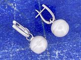 une paire de boucles d'oreilles en perles blanches posées sur une surface en marbre bleu