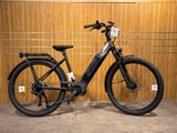 une photo d'un vélo électrique noir garé devant un mur en bois