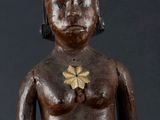 an image of a wooden statue of a man with a flower on his chest