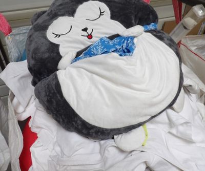 a stuffed penguin that is laying on a pile of clothes