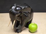 a black elephant statue next to an apple on a table