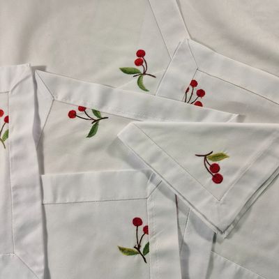 quatre serviettes blanches ornées de cerises rouges et de feuilles vertes