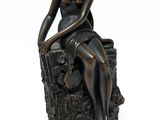 statue of a woman sitting on a tree stump with her hands on her knees