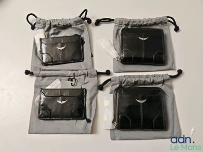 trois portefeuilles en cuir noir posés sur une table blanche