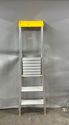 un gros plan d'un escabeau jaune et argent adossé à un mur