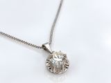 un gros plan d'un collier en diamants posé sur une surface blanche