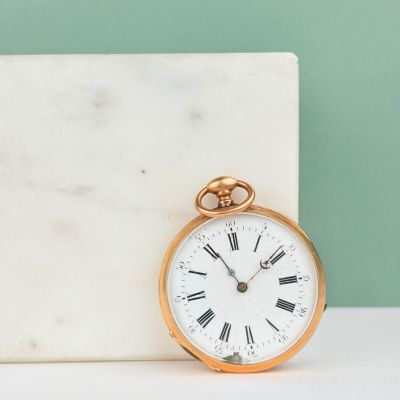 une montre de poche en or posée sur un bloc de marbre