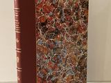 un livre à la couverture rouge posé sur une table blanche