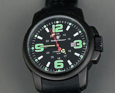 une montre noire avec des chiffres verts, posée sur une table