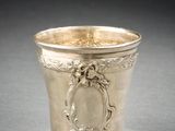 une coupe en argent ancienne posée sur une table, devant un fond noir