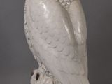 an image of a white owl statue sitting on top of a tree stump