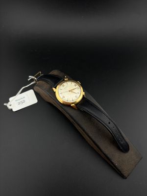a close up of a watch on a black surface with a tag