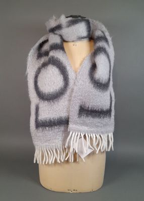 grey and white scarf with circles and fringes on a mannequin head