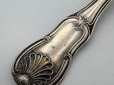 an old silver spoon with a design on it sitting on a table
