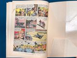 someone is holding a comic book open on a blue surface