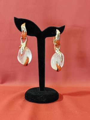gros plan d'une paire de boucles d'oreilles sur un support noir