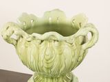a green vase sitting on top of a wooden table