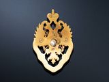 an image of a gold brooch with a pearl in the center
