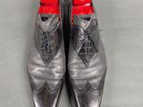 pair of men ' s shoes with red soles sitting on a gray surface